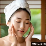 피부 자극 완화 팁 - A serene Japanese woman with sensitive skin gently washing her face using a creamy, milk-type cleans...